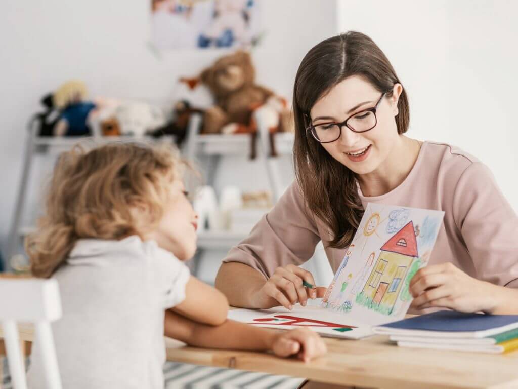 Nanny som visar upp en hemmagjord teckning för liten flicka som sitter mittemot